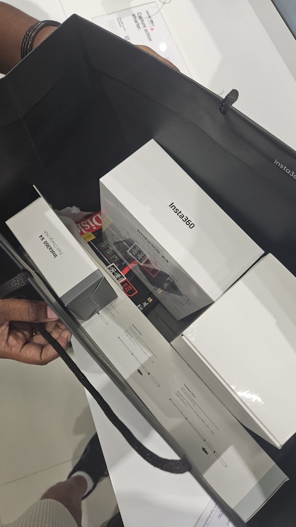 A shopping bag filled with new Insta360 X4 cameras and accessories, held by a customer.