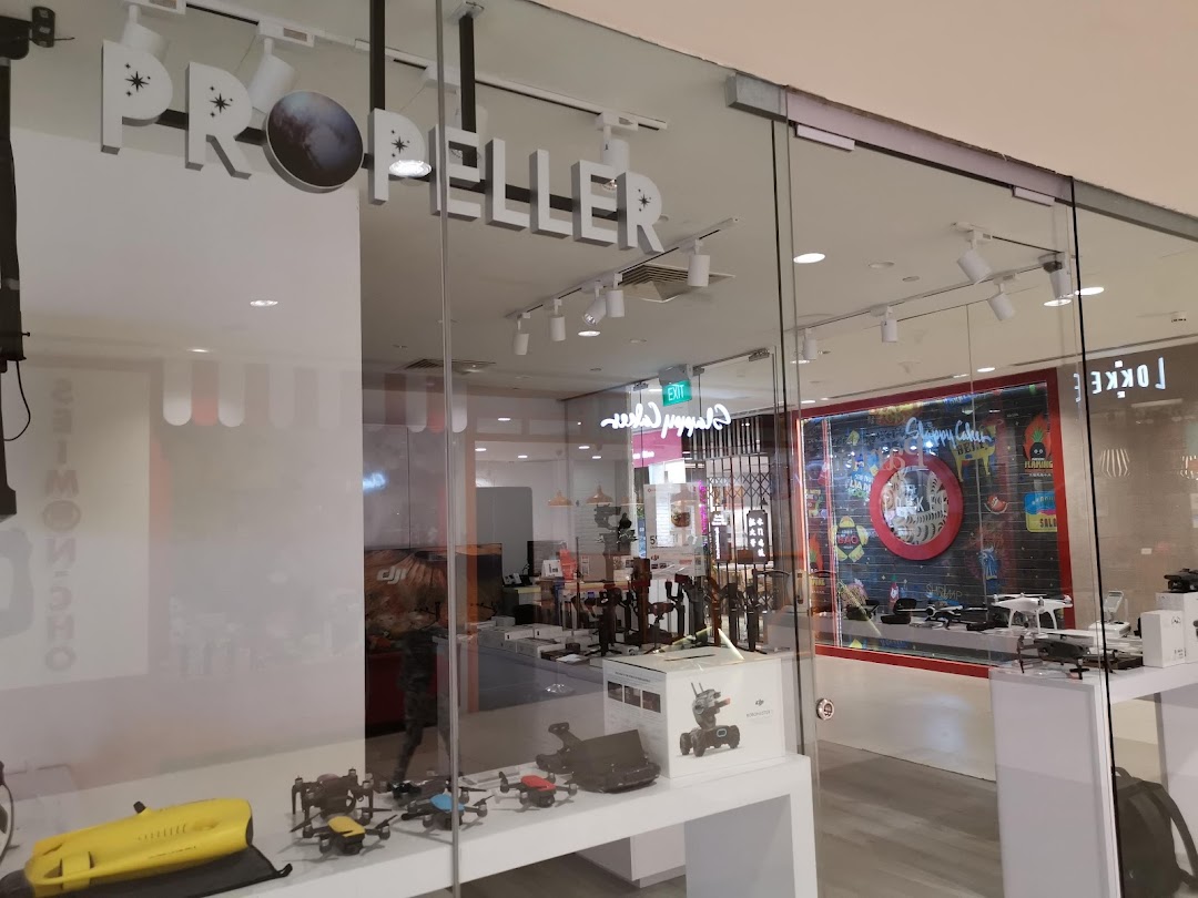 The glass storefront of Propeller Singapore, showcasing drones and tech products in its display window.