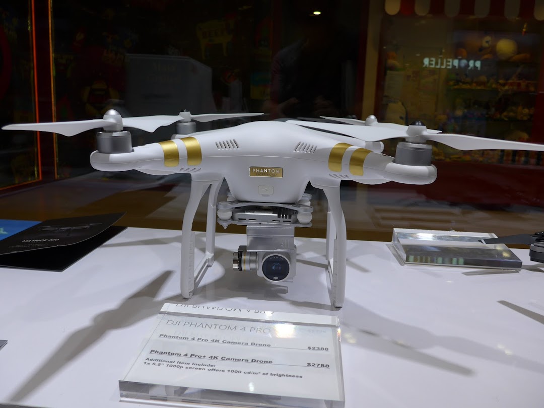 A white DJI Phantom drone is showcased on display with pricing details in a retail setting.
