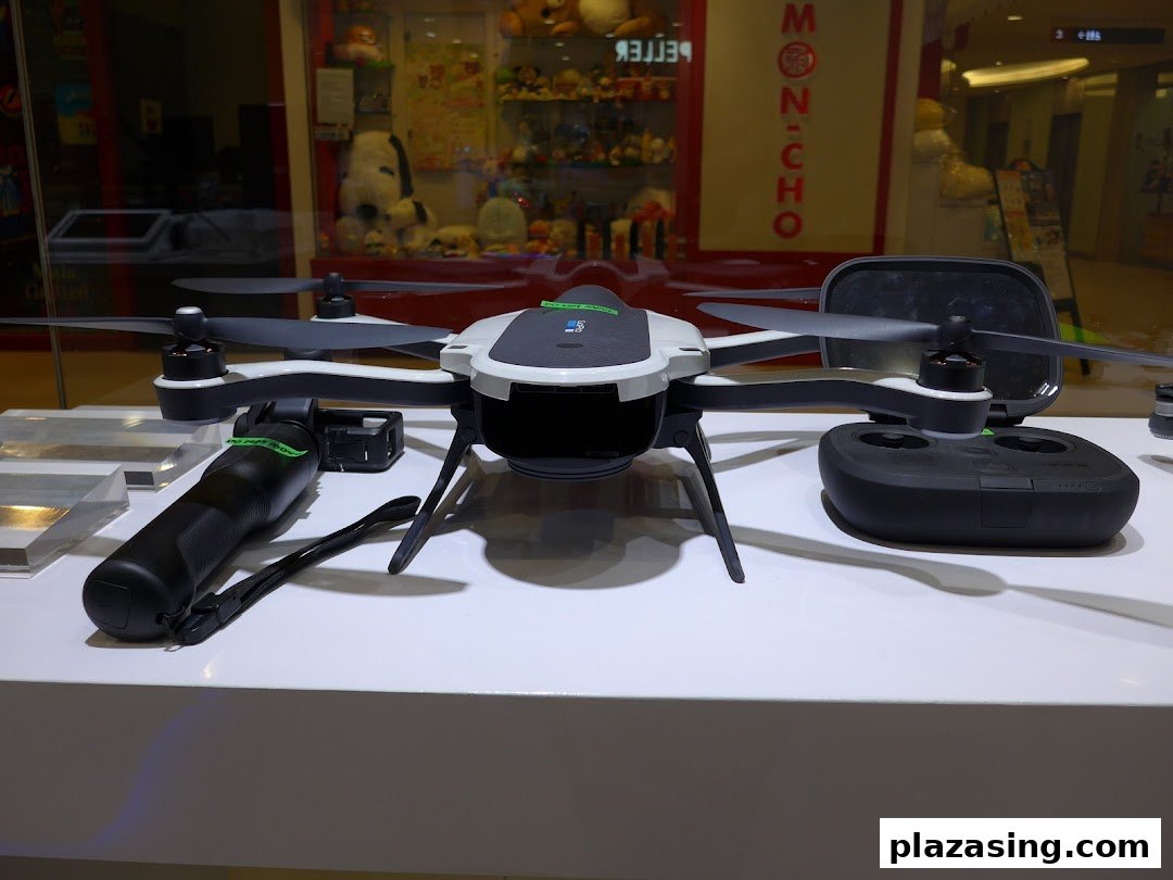 A white and black drone with its remote control and accessories displayed on a white counter.