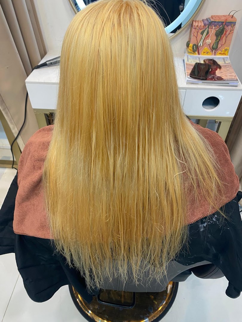 A customer's long blonde hair being treated in a salon chair, showcasing hair services.