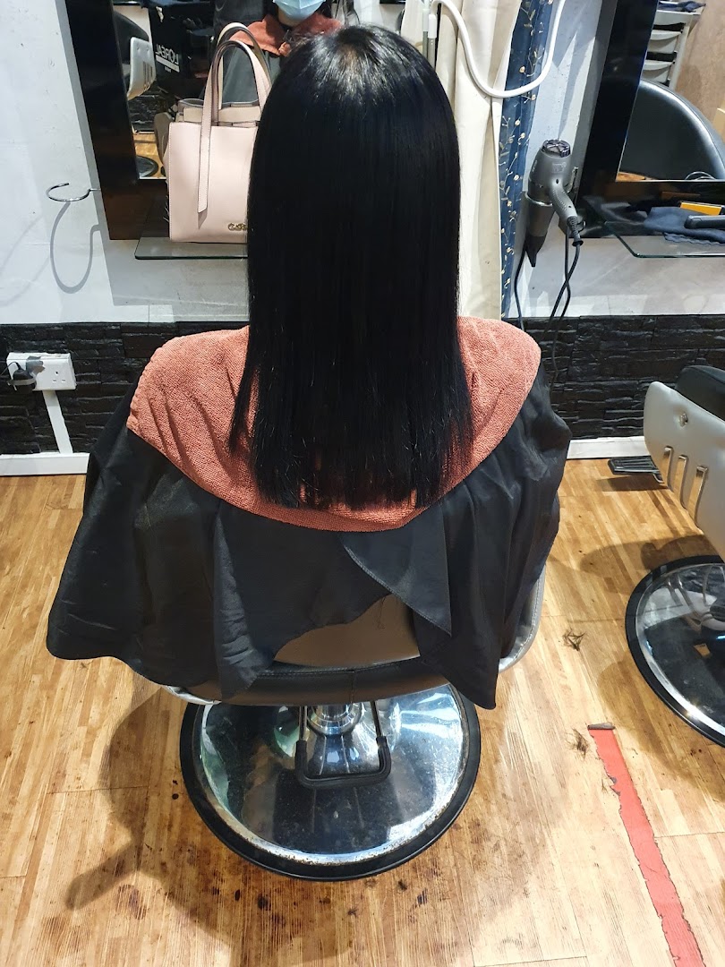 A client with freshly styled, straight black hair sitting in a salon chair at Pure Express Salon.