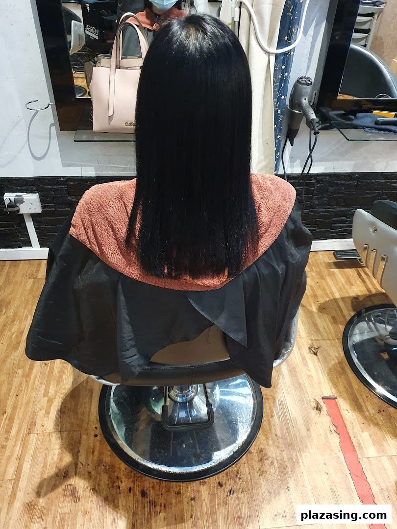 A client with freshly styled, straight black hair sitting in a salon chair at Pure Express Salon.