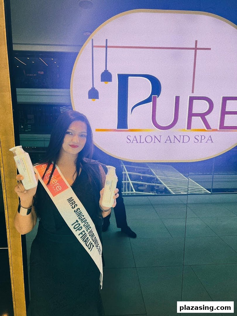 A woman, wearing a 'Mrs Singapore Worldwide Top Finalist' sash, holds beauty products in front of Pure Salon and Spa.