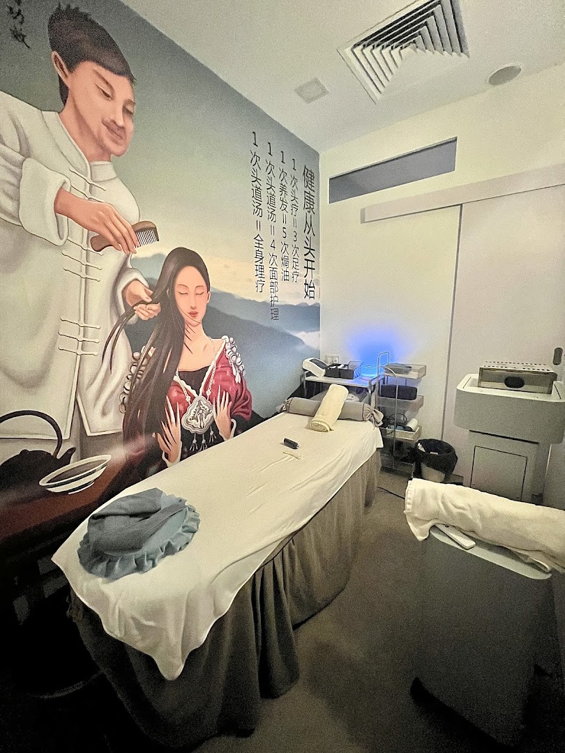 An interior view of a serene wellness treatment room with a large wall mural and massage bed.