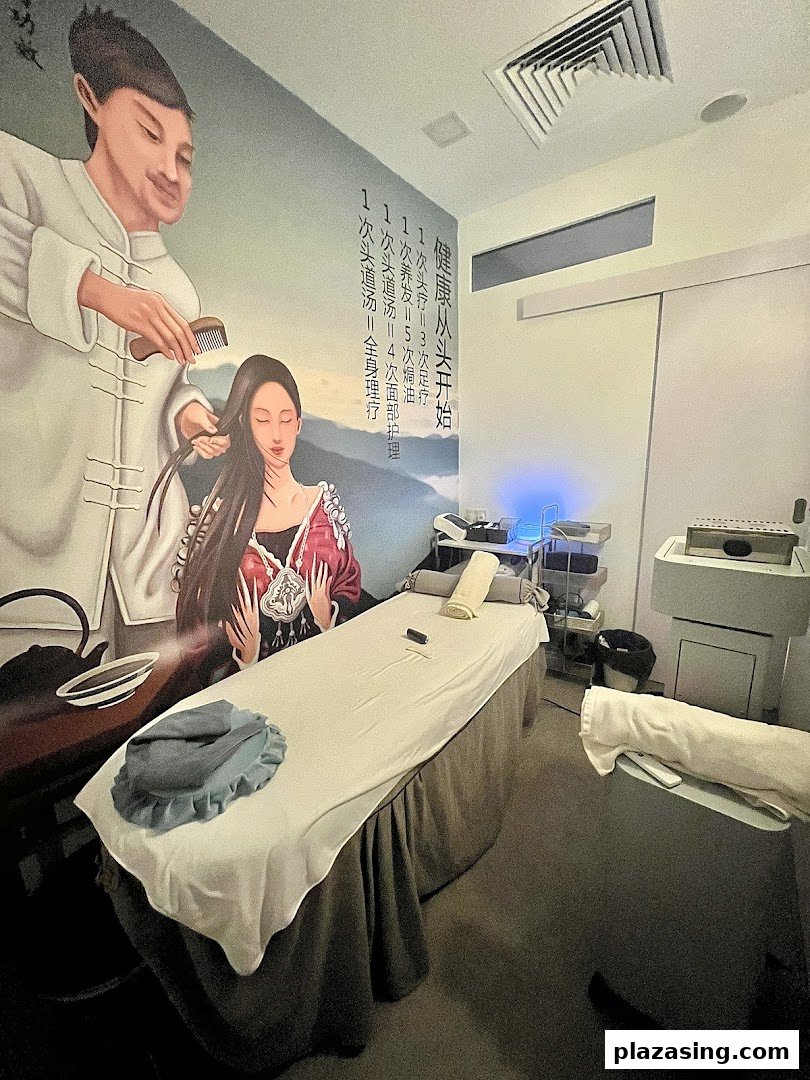 An interior view of a serene wellness treatment room with a large wall mural and massage bed.
