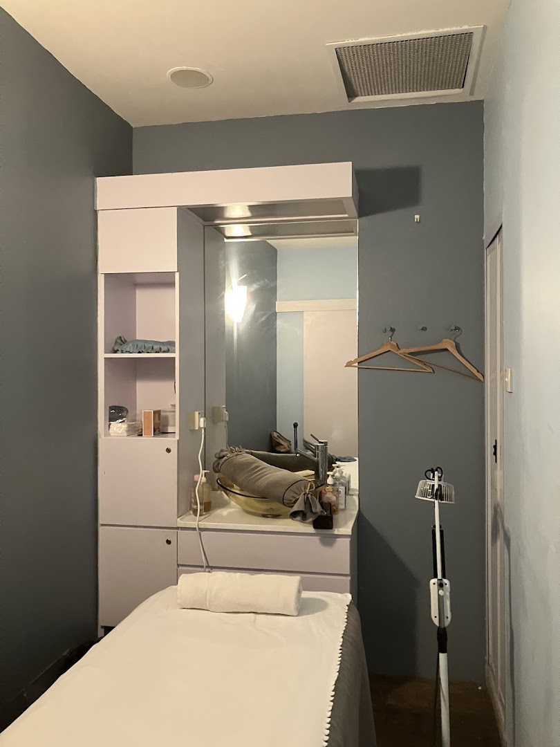 A serene treatment room at Refresh TCM Wellness, featuring a bed, mirror, and sink for therapeutic sessions.