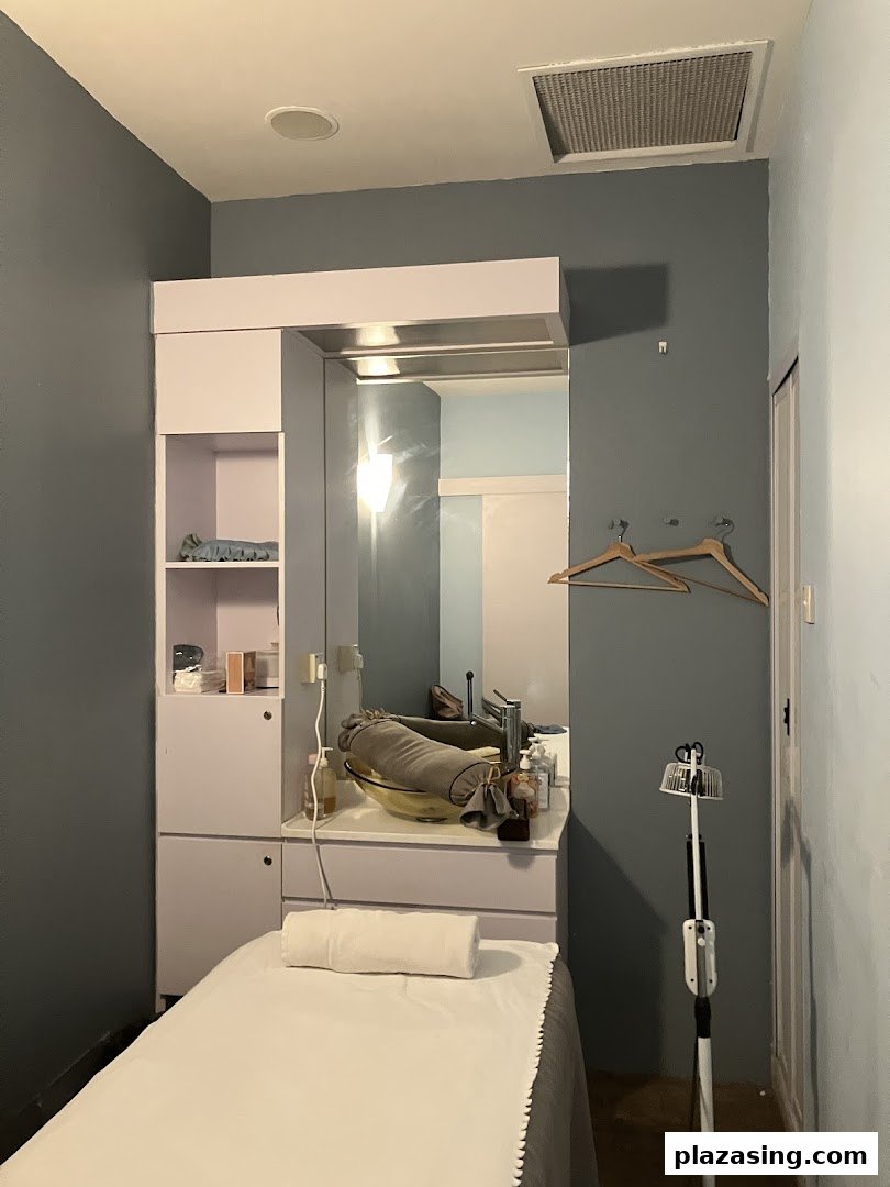 A serene treatment room at Refresh TCM Wellness, featuring a bed, mirror, and sink for therapeutic sessions.
