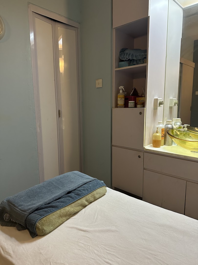 An interior view of a serene treatment room with a massage bed and cabinet.