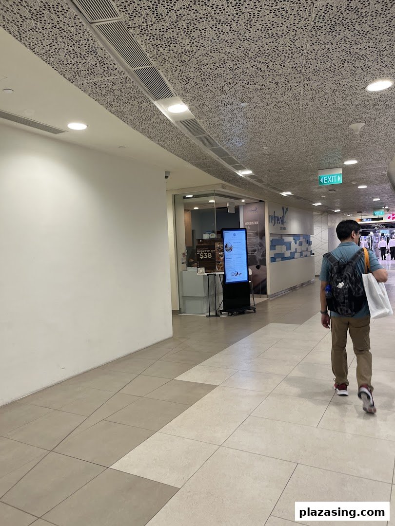 A person walks past the inviting entrance of Refresh TCM Wellness in a modern shopping mall.