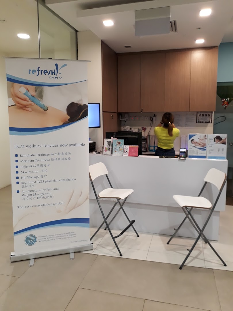 A reception area with a staff member and a promotional banner for TCM wellness services.