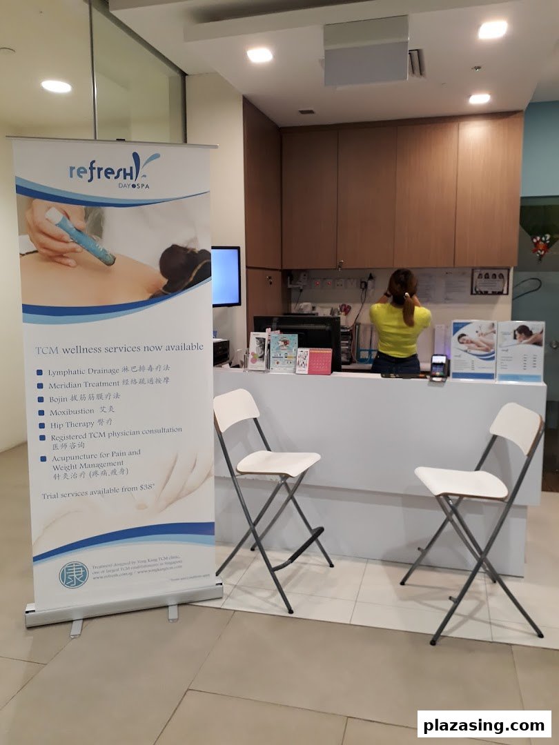 A reception area with a staff member and a promotional banner for TCM wellness services.