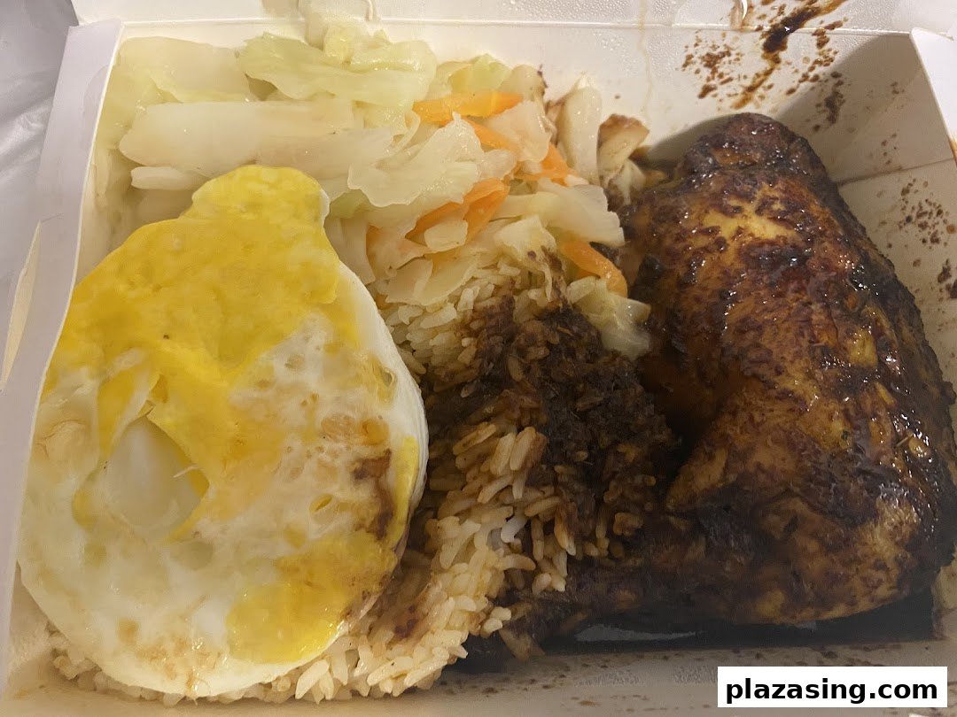 A delicious Indonesian BBQ meal in a takeout box, featuring chicken, rice, egg, and vegetables.