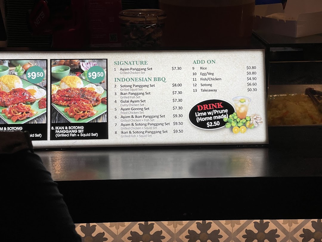 A brightly lit menu board displaying various Indonesian BBQ dishes, add-ons, and a homemade drink.