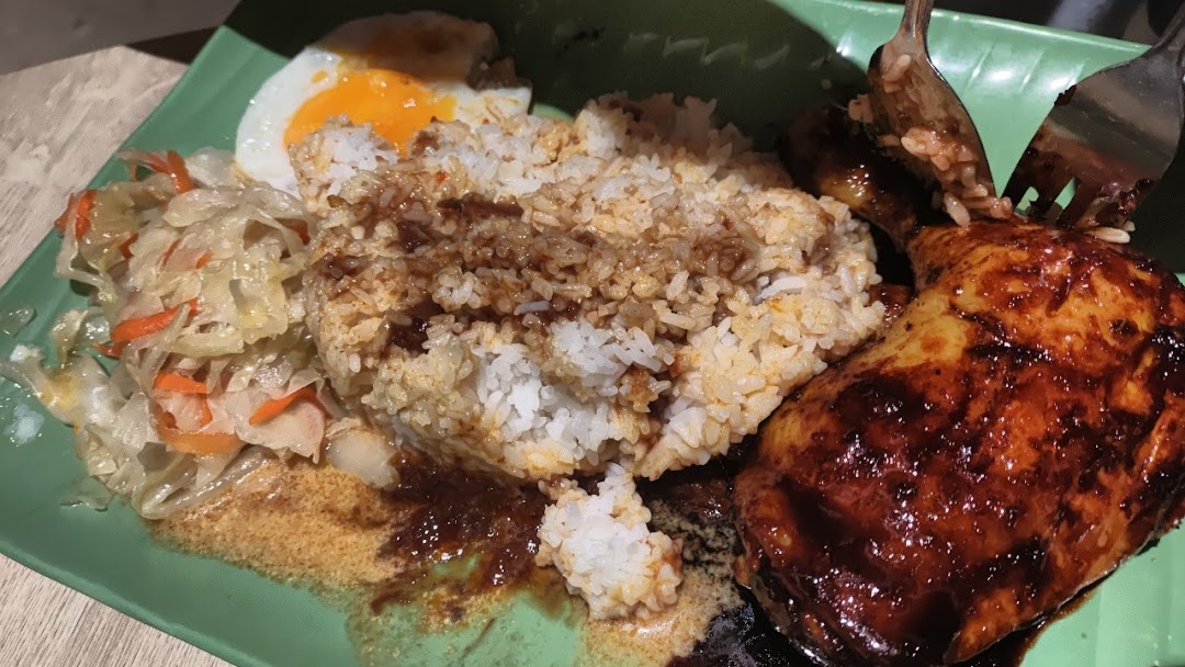 A delicious plate of Indonesian BBQ chicken with rice, a fried egg, and pickled vegetables.