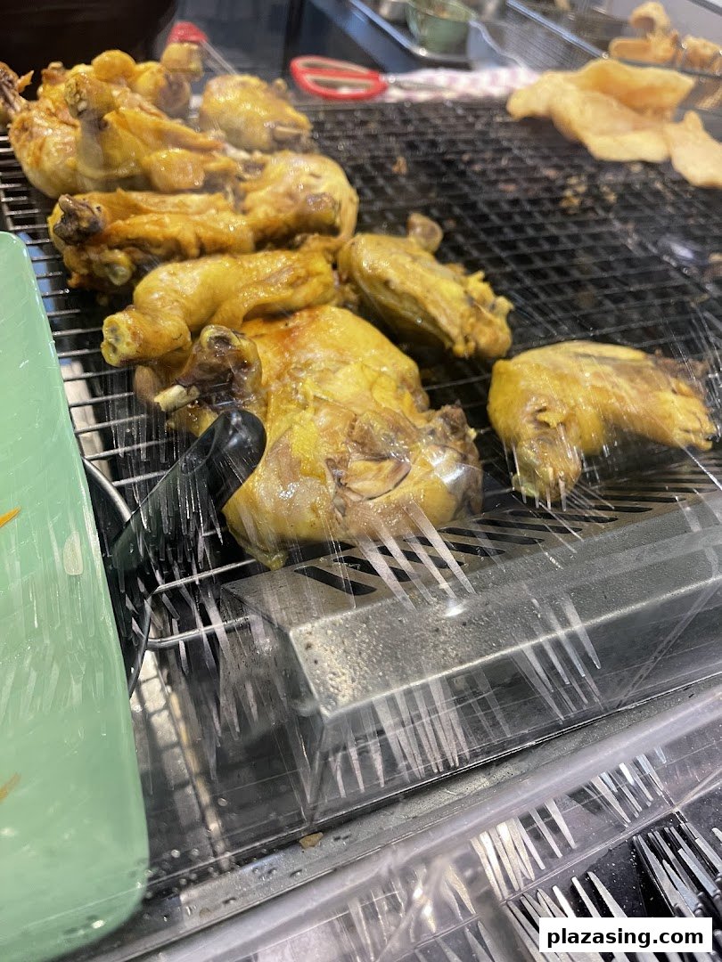 Close-up of golden-brown grilled chicken pieces displayed on a rack, covered with plastic wrap.