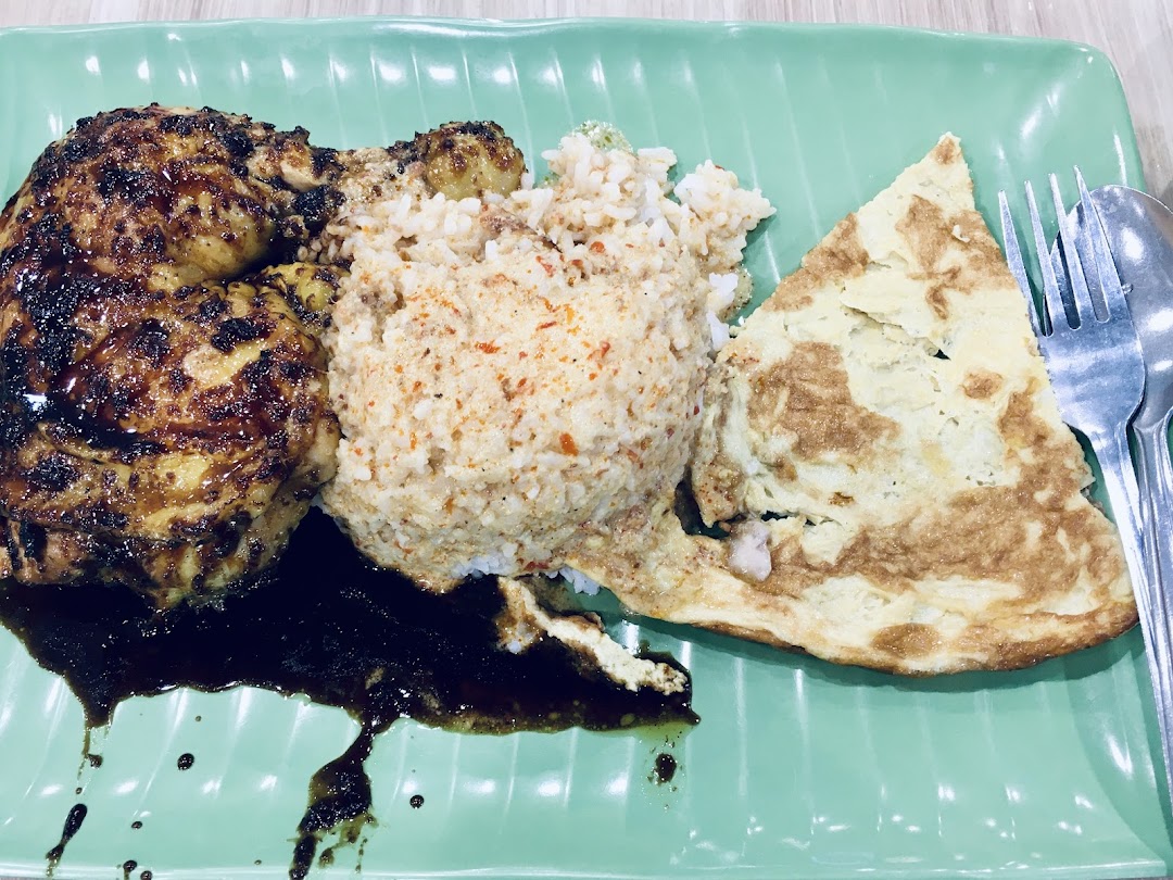 A plate of grilled chicken, spiced rice, and an omelet, served with a rich dark sauce.