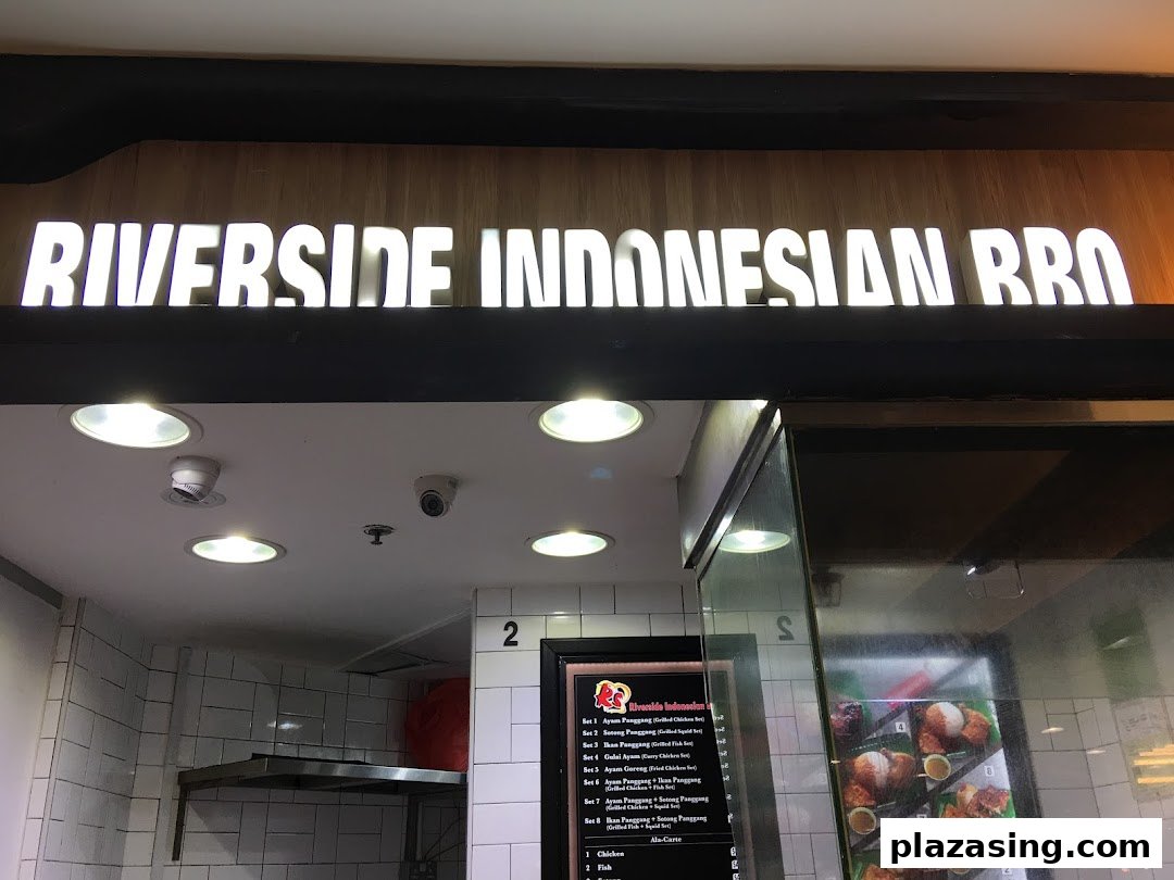 Illuminated sign for Riverside Indonesian BBQ above the shop entrance.