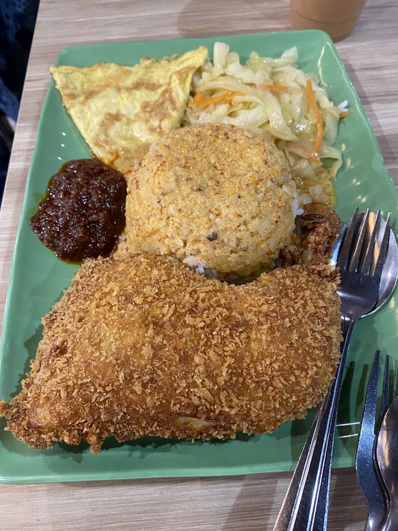 A vibrant plate of Indonesian fried chicken, rice, sambal, omelet, and vegetables.