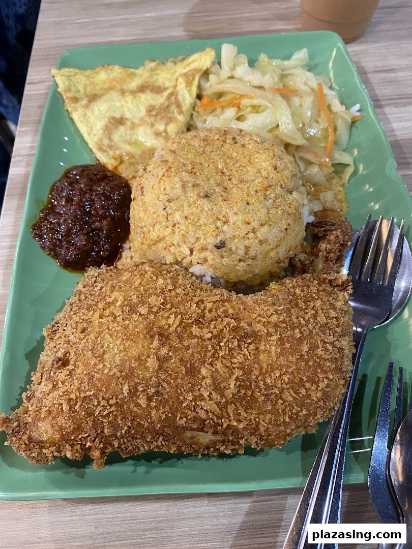 A vibrant plate of Indonesian fried chicken, rice, sambal, omelet, and vegetables.