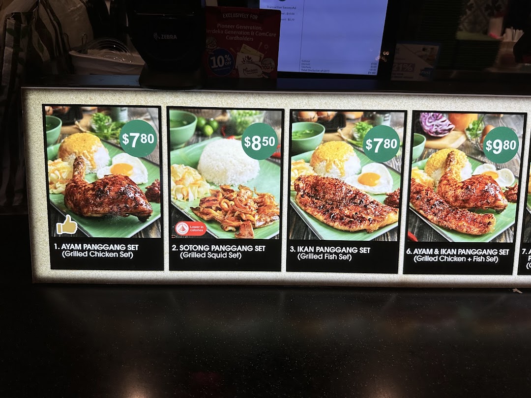 A brightly lit menu board displaying various Indonesian grilled food sets with prices.