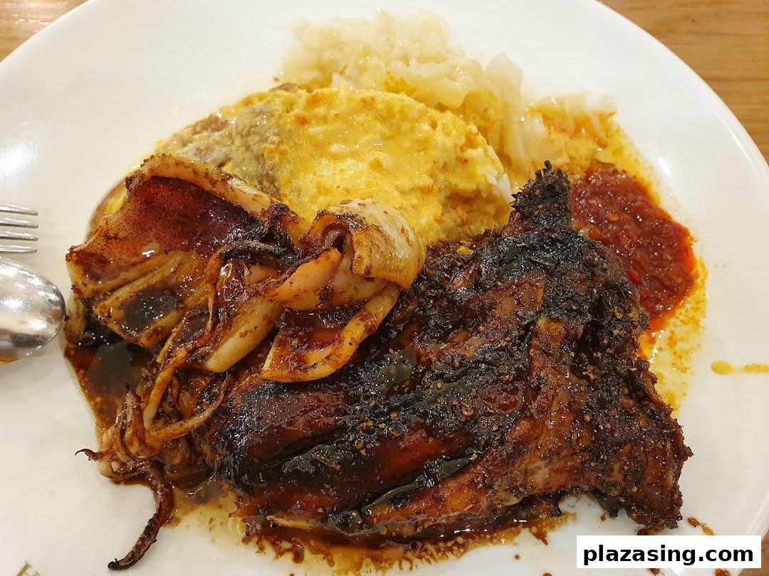 A plate of grilled Indonesian BBQ chicken and squid with rice, omelette, and sambal.