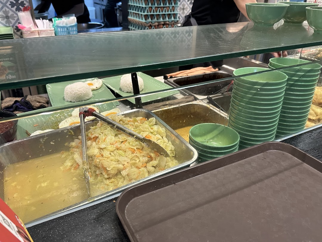 A vibrant food counter showcasing fresh Indonesian dishes like rice, eggs, and vegetables.