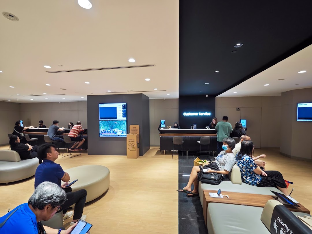 Customers wait and interact with staff at the Samsung Service Centre's modern customer service area.