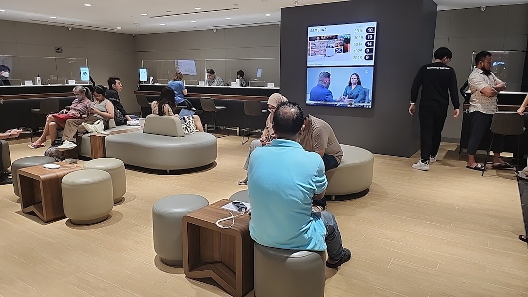 Customers wait and staff assist in a modern Samsung Service Centre with comfortable seating.