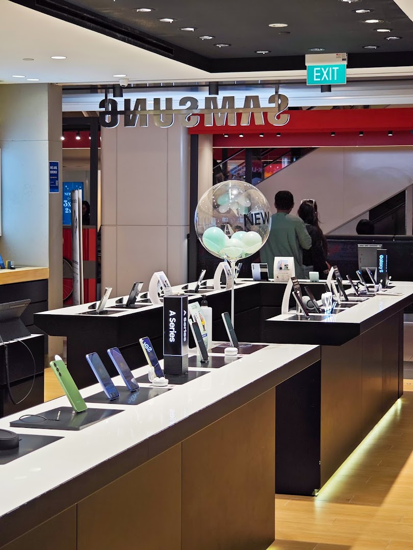 Interior view of a Samsung store showcasing various mobile devices and accessories on display tables.