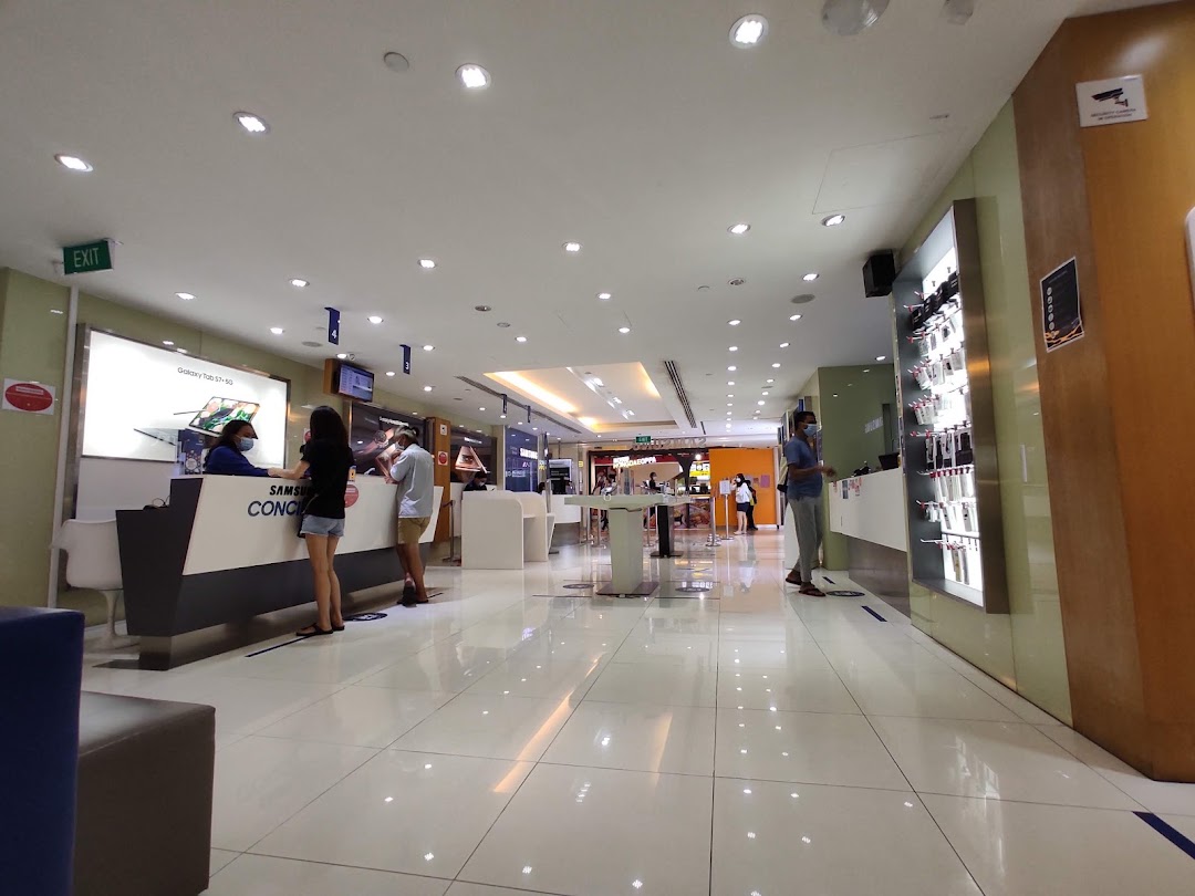 Interior view of a Samsung Service Centre with customers at the counter and product displays.