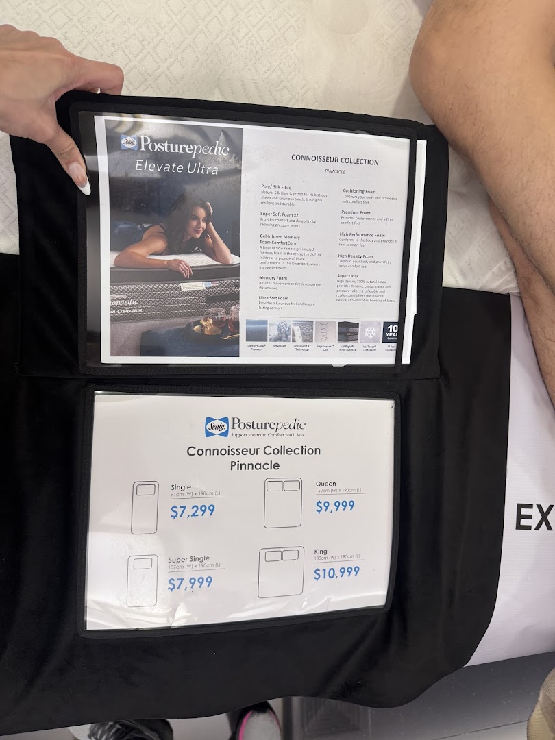 A close-up of Sealy Posturepedic mattress product information and pricing displayed in a showroom.