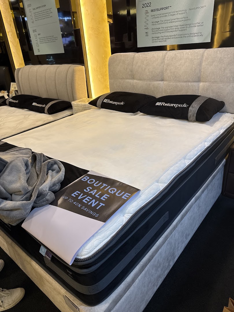 An interior view of Sealy Sleep Boutique showcasing mattresses and beds, with a 'Boutique Sale Event' sign.
