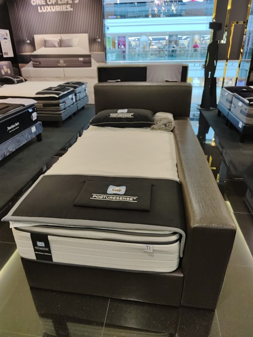 A display of a Sealy Posturepedic mattress and bed frame inside the Sealy Sleep Boutique showroom.