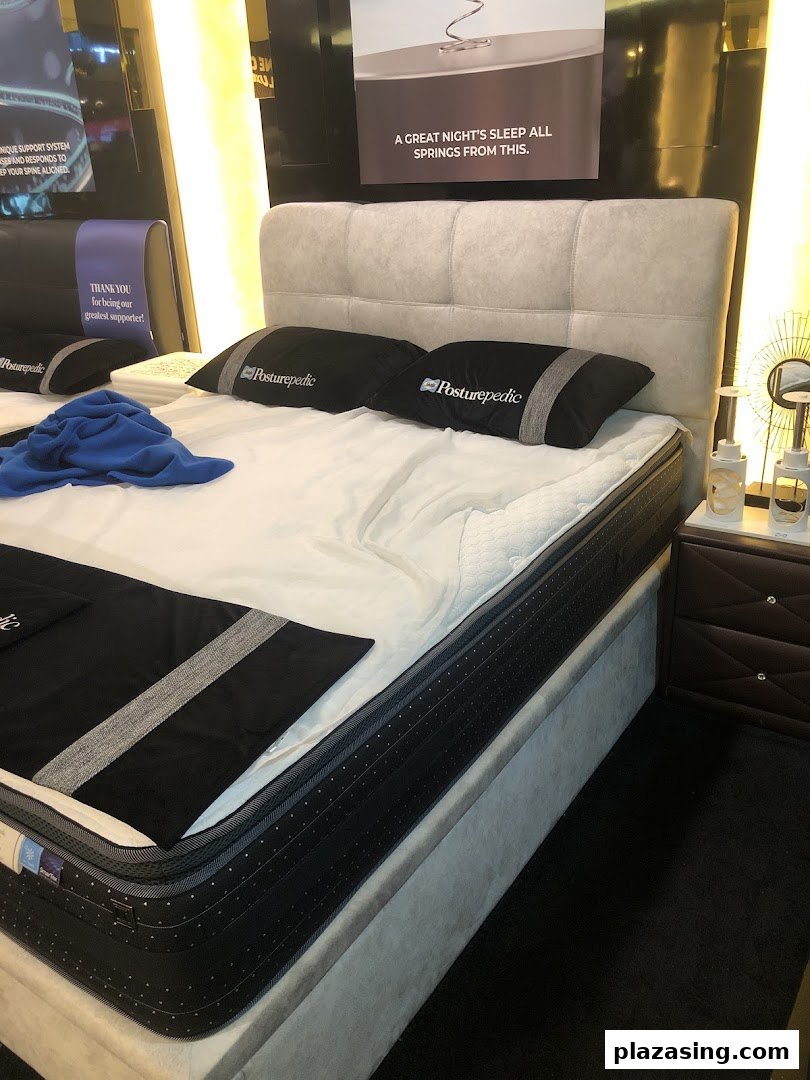 A display bed featuring a Sealy Posturepedic mattress and pillows, highlighting sleep comfort.