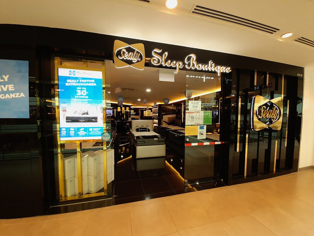 The illuminated entrance of Sealy Sleep Boutique showcasing mattresses and a festive sale promotion.