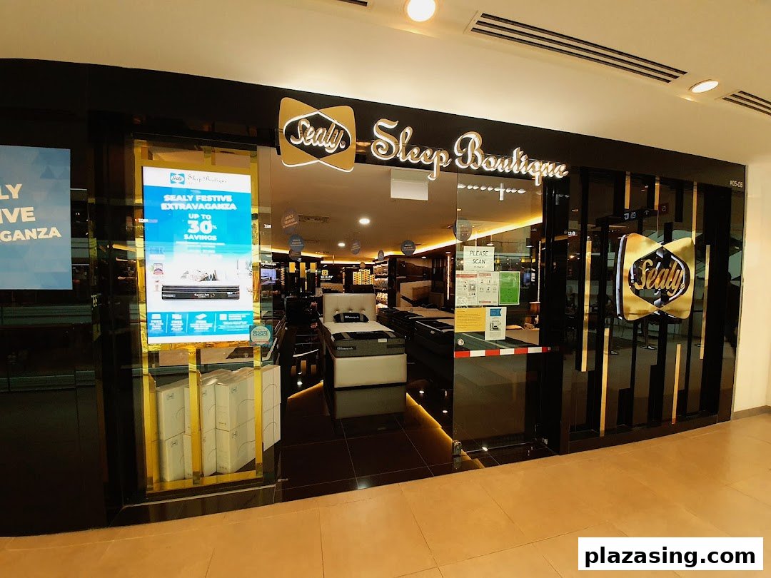 The illuminated entrance of Sealy Sleep Boutique showcasing mattresses and a festive sale promotion.
