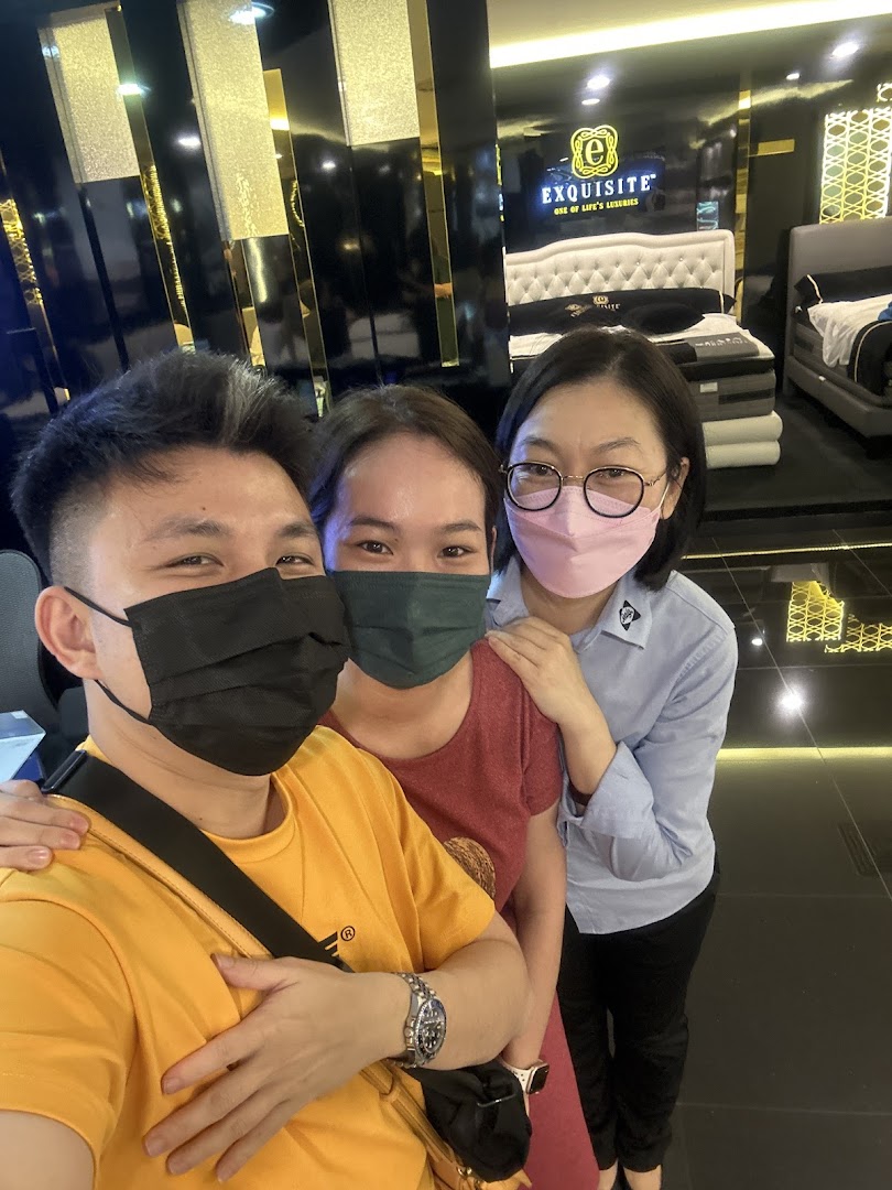 Three people, two masked, pose for a selfie inside a luxurious mattress and bedding showroom.
