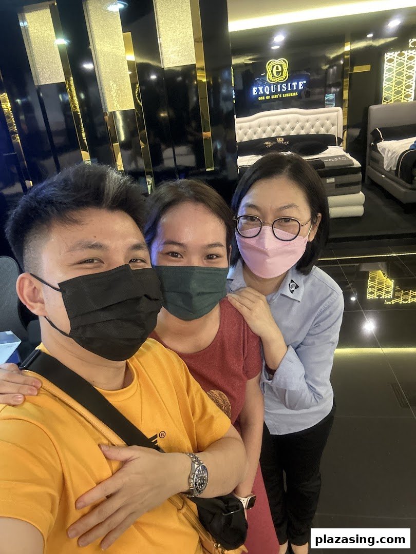 Three people, two masked, pose for a selfie inside a luxurious mattress and bedding showroom.