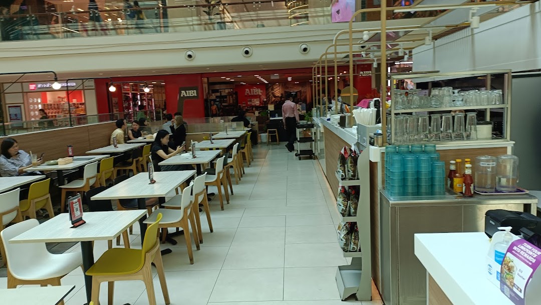 An interior view of Secret Recipe, showing customers dining at tables and a service counter.