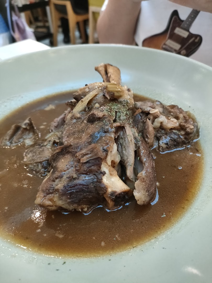 A close-up of a hearty braised meat dish, possibly lamb shank or oxtail, in a rich brown gravy.