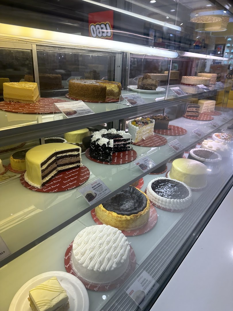 A vibrant display case showcasing a wide variety of delicious cakes and cheesecakes at Secret Recipe.