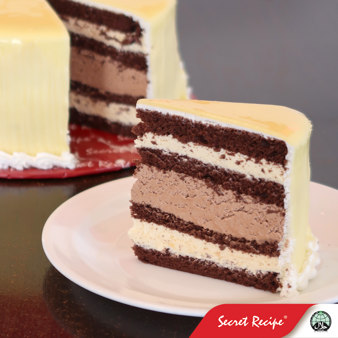 A delicious slice of multi-layered chocolate and cream cake with a glossy white chocolate glaze.