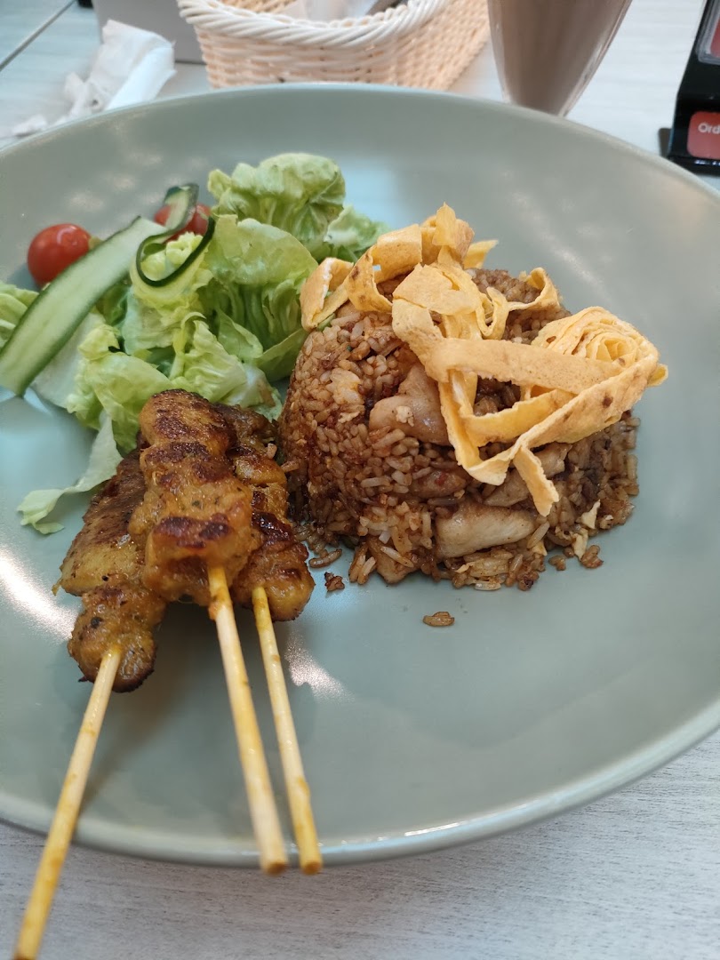 A plate of fried rice with chicken satay skewers and a fresh side salad.