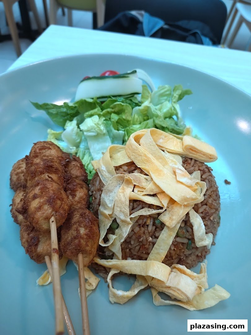 A plate of fried rice with egg strips, skewers, and a fresh side salad.