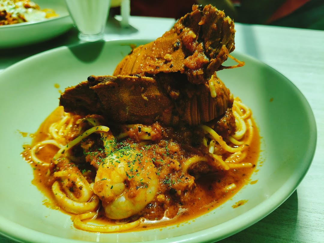 A vibrant seafood pasta dish featuring a large crustacean, shrimp, and squid in a rich red sauce.