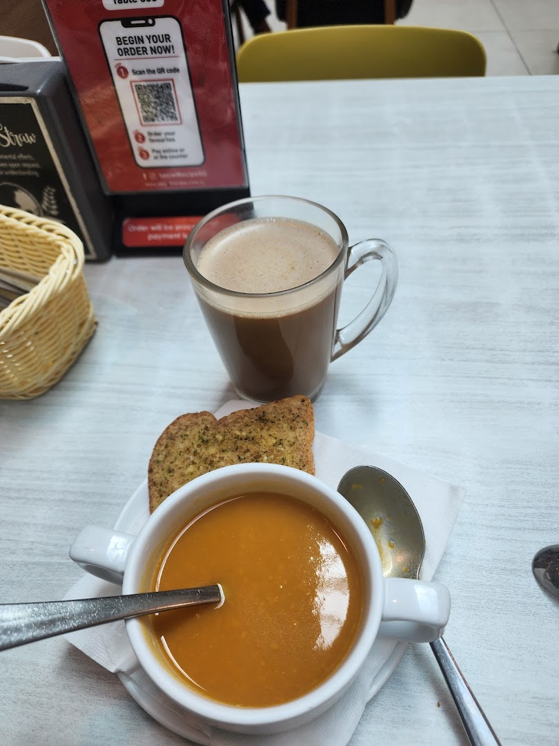 A warm bowl of soup, garlic bread, and a hot chocolate on a table at Secret Recipe.