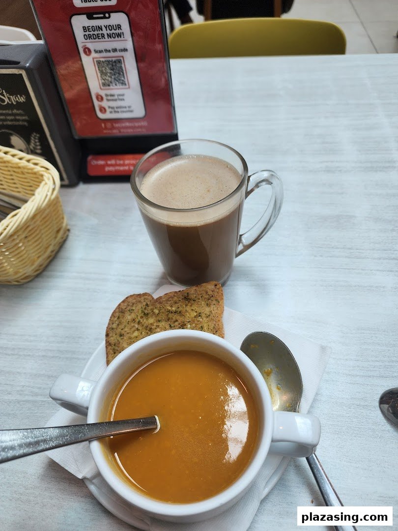 A warm bowl of soup, garlic bread, and a hot chocolate on a table at Secret Recipe.