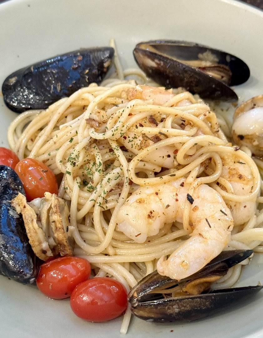 A delicious plate of seafood pasta featuring mussels, shrimp, and cherry tomatoes.