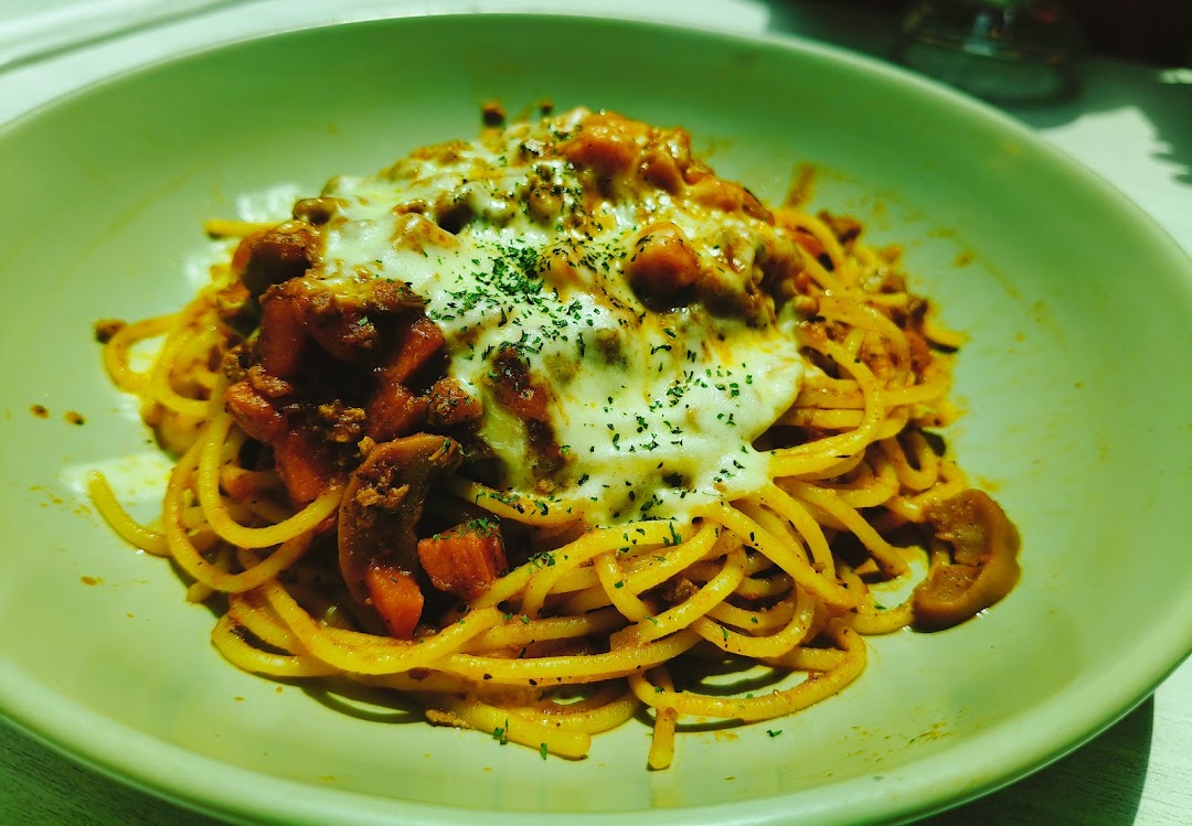 A delicious plate of spaghetti bolognese topped with melted cheese and herbs.